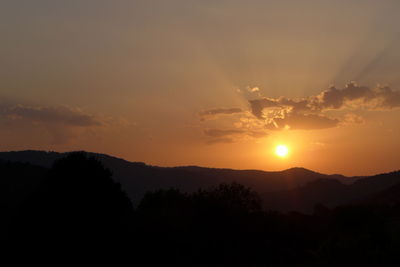 Scenic view of silhouette mountains against orange sky