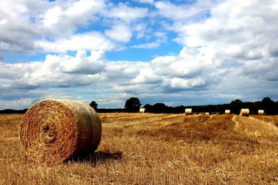 Hay bales on field against sky