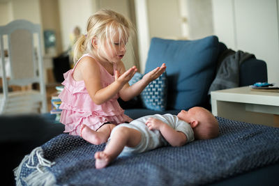 Sister with baby boy on bed at home