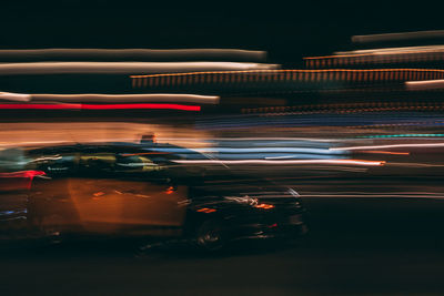 Car amidst light trails on road at night