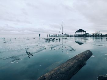 Pier on sea against cloudy sky