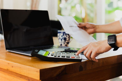 Midsection of man using calculator while working at table