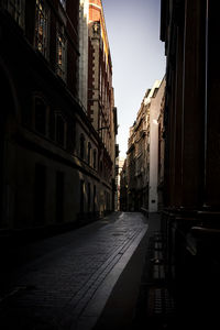Empty road amidst buildings in city against sky