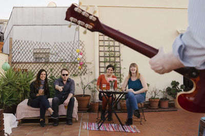 Smiling couple holding beer glass sitting on chair outdoors