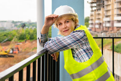 Portrait of woman standing against railing