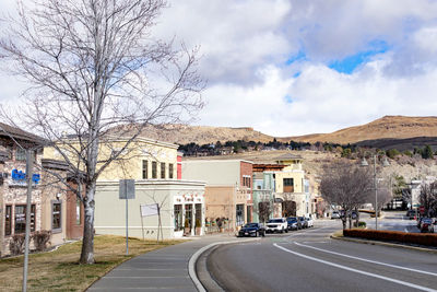 Road by buildings in city against sky