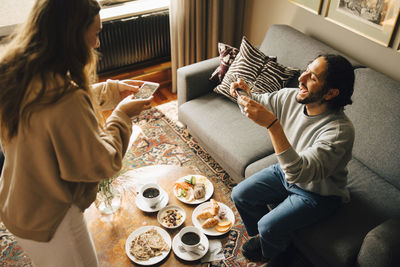 Couple photographing breakfast with smart phones in hotel room