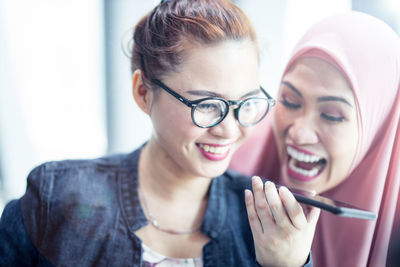 Happy friends talking on smart phone at home