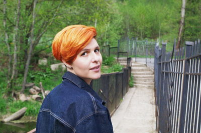 Portrait of woman standing by fence
