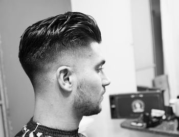 Close-up of young man looking away while siting at barber shop