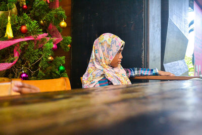 Woman sitting by christmas tree