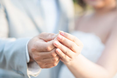 Midsection man putting ring to bride during wedding ceremony