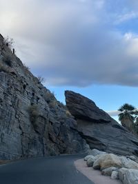 Rock formations by road against sky