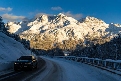 Road amidst snowcapped mountains against sky during winter