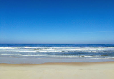 Scenic view of beach against clear blue sky