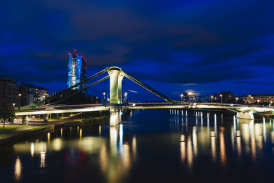 Illuminated bridge over river against sky at night