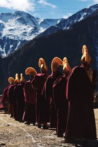 Rear view of monks standing by snowcapped mountain