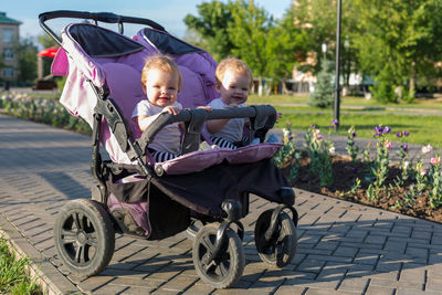 Twins in a baby carriage on a walk in the city park in the summer.