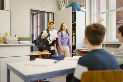 Smiling male and female students entering in classroom