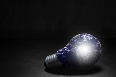 Close-up of light bulb on table against black background