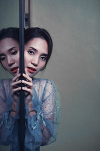 Portrait of young woman by mirror with reflection