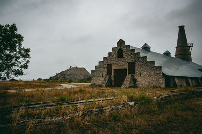 Old factory on field against sky