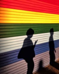 Shadow of man on multi colored umbrella