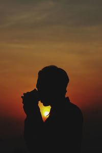 Silhouette man standing against orange sky during sunset