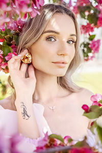 Portrait of a beautiful romantic young woman in close-up with pink flowers of a blooming apple tree. 