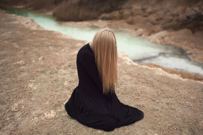 Rear view of woman sitting at beach