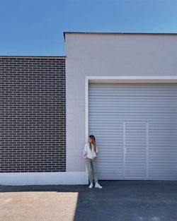 Minimalistic portrait of a woman standing at building exterior