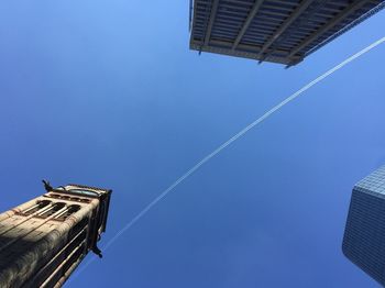 Low angle view of old city hall and buildings against vapor trail in clear sky