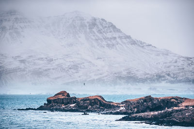 Scenic view of snowcapped mountain by sea against sky