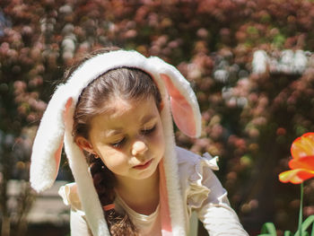 Portrait of a beautiful caucasian girl with a headband with bunny ears collects scattered easter egg
