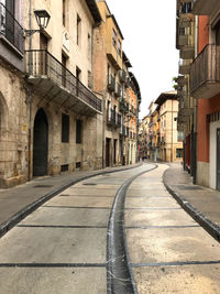 Empty road amidst buildings against sky in city