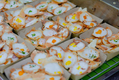 Thai coconut pancake with yellow corn topping in brown paper plate.