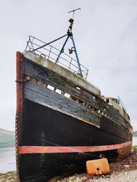 Abandoned ship moored in water against sky