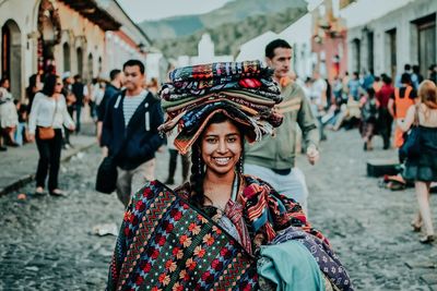 Portrait of smiling woman with arms outstretched in city