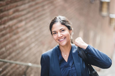 Portrait of businesswoman with bag standing in city