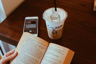 High angle view of hand holding book on table