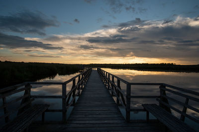 Pier over lake against sky during sunset