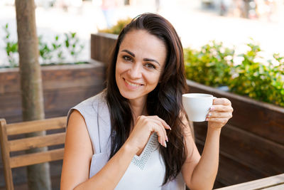 Positive business woman sitting in outdoor cafe drinking coffee.
