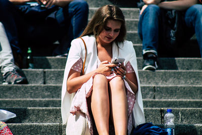 Midsection of woman using mobile phone while sitting outdoors