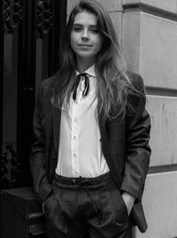 Beautiful young woman standing against wall