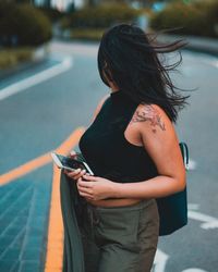 Rear view of woman standing on road