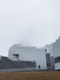 Man on modern building against sky in city