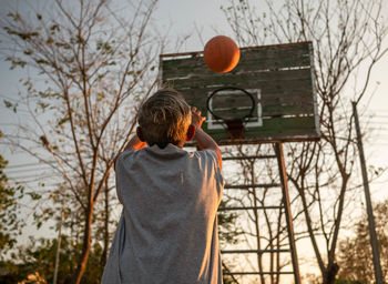 Rear view of man standing by basketball hoop