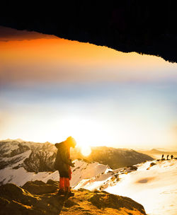 Woman standing by mountain against sky during sunset