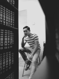 Portrait of young man sitting on table in office