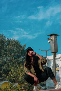 Young woman sitting against sky